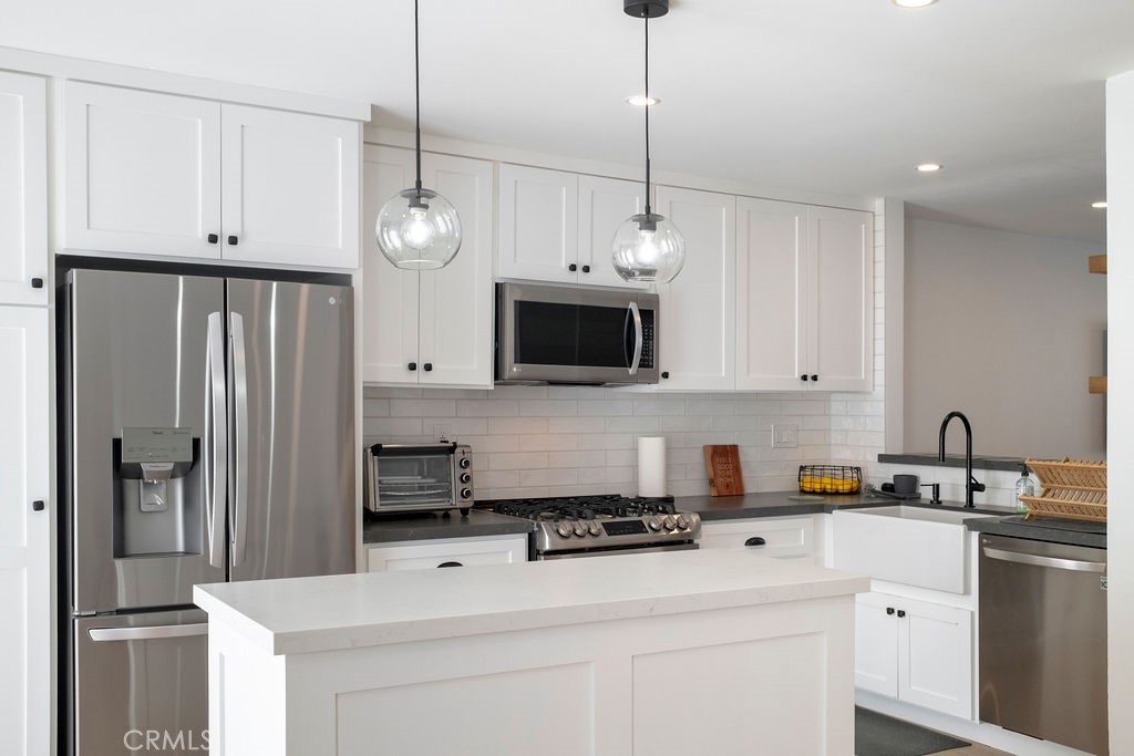 Kitchen showing included counterdepth refrigerator, quartz counters, updated tile backsplash, and Shaws farmhouse sink. - 25655 Paseo La Cresta 47, Laguna Niguel CA 92677 - photo 12