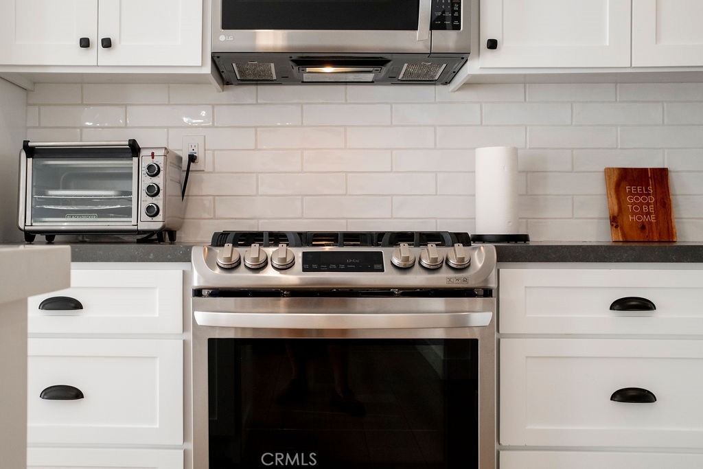 Close up view of gas range, oven subway tile backsplash, soft closing cabinets and drawers. - 25655 Paseo La Cresta 47, Laguna Niguel CA 92677 - photo 13