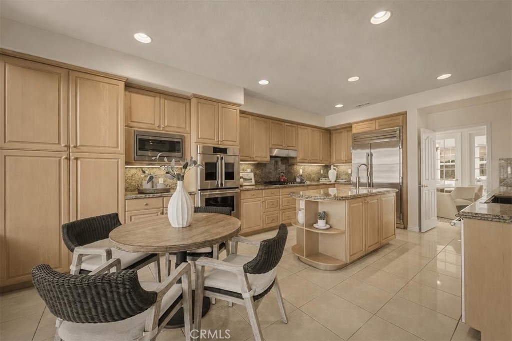 A gourmet kitchen of warm honey cabinetry, granite surfaces, and premium stainless appliances, anchored by a sculpted is - 28932 Drakes Bay, Laguna Niguel CA 92677 - photo 13