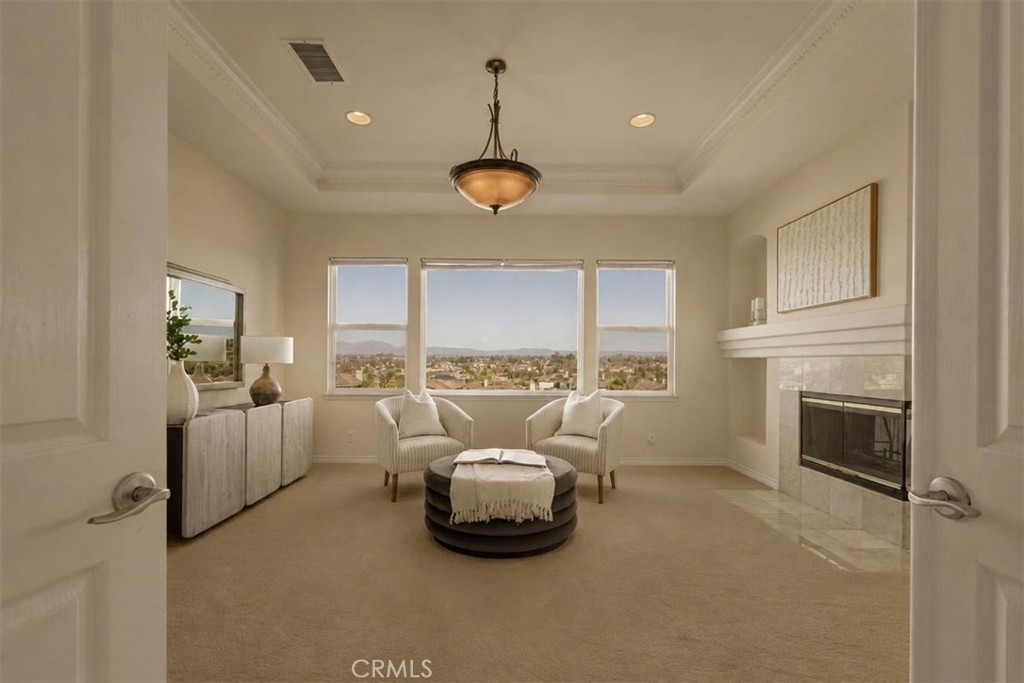 A grand primary suite sitting area with a tray ceiling, three-sided fireplace, and commanding panoramic views through ex - 28932 Drakes Bay, Laguna Niguel CA 92677 - photo 15