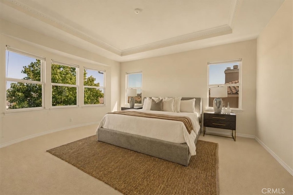 A tranquil primary bedroom with a curved bay window, ornate crown molding, and sweeping hillside, neighborhood, and moun - 28932 Drakes Bay, Laguna Niguel CA 92677 - photo 17