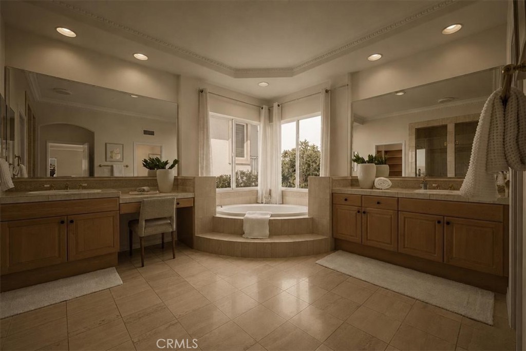 A palatial primary bath with a sunken soaking tub, dual vanities, and a dedicated makeup desk beneath a tray ceiling. - 28932 Drakes Bay, Laguna Niguel CA 92677 - photo 18