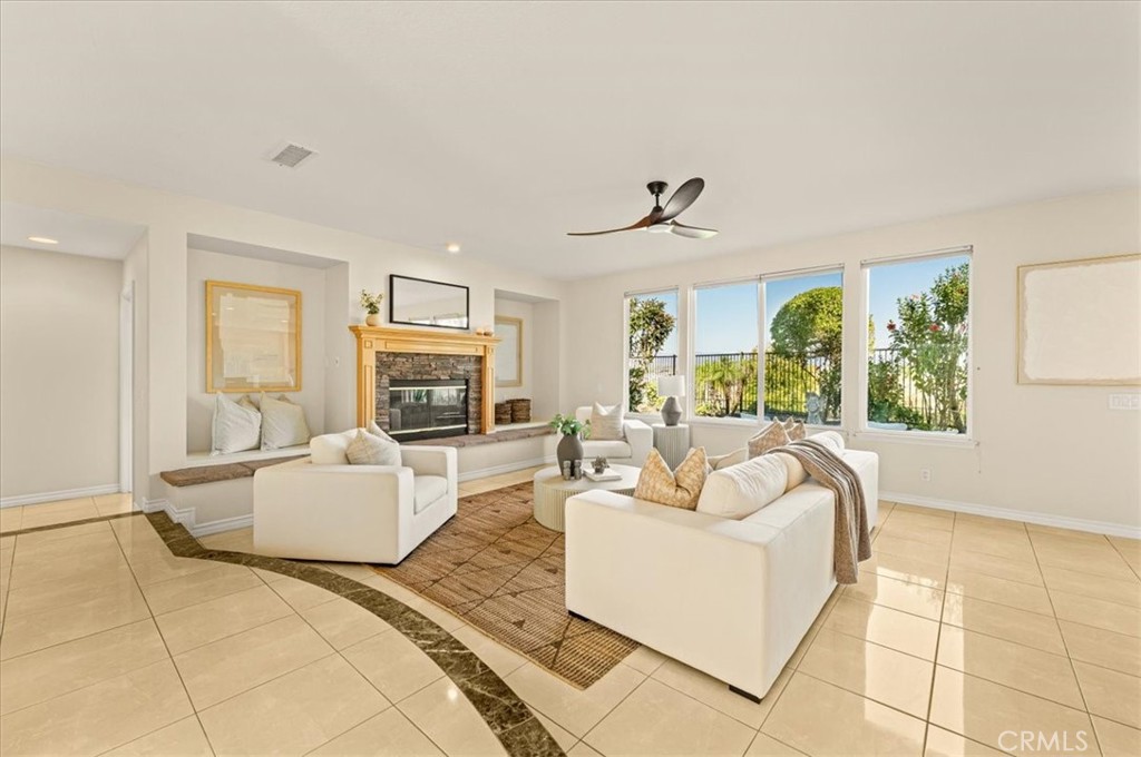 A sun-drenched living room with polished tile floors and a stately fireplace. - 28932 Drakes Bay, Laguna Niguel CA 92677 - photo 27