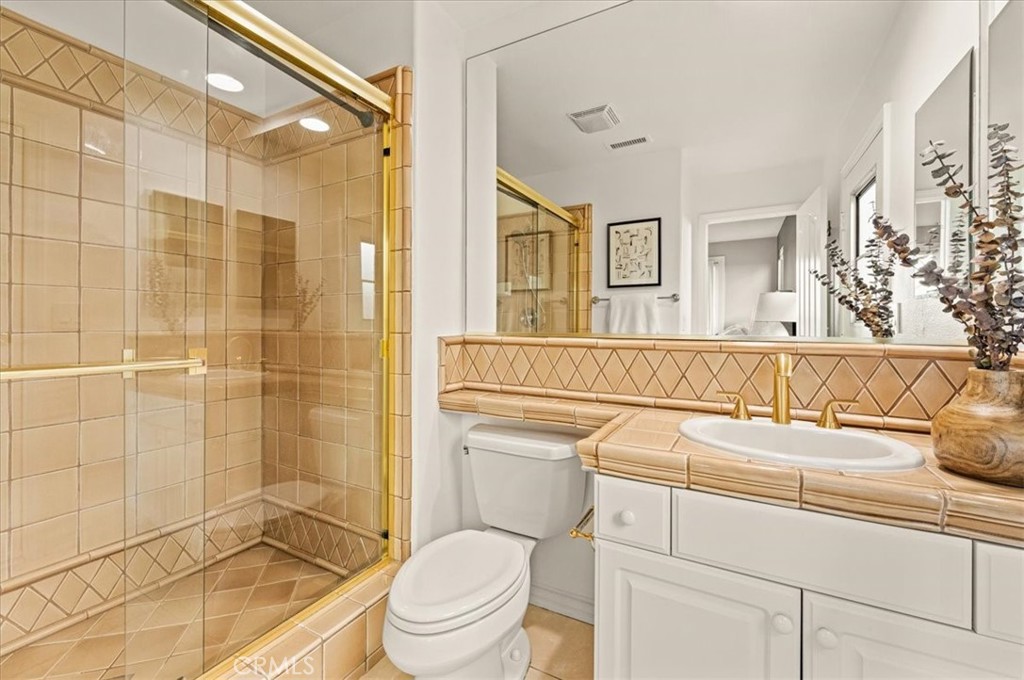 A refined primary bath with golden fixtures, intricate tilework, and a glass-enclosed shower - 28932 Drakes Bay, Laguna Niguel CA 92677 - photo 36