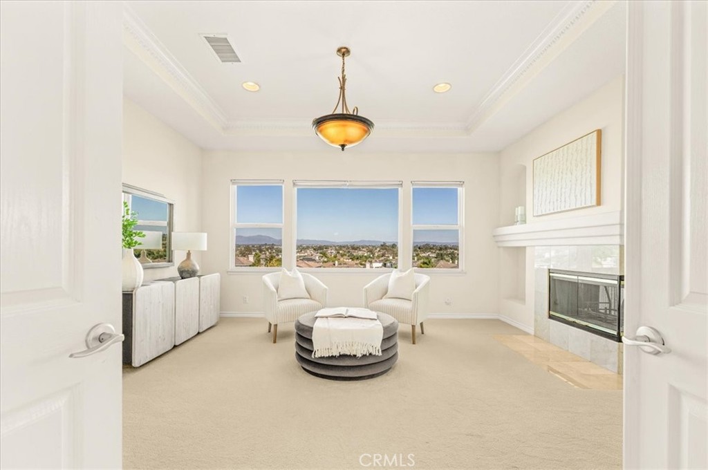 A grand primary suite sitting area with a tray ceiling, three-sided fireplace, and commanding panoramic views through ex - 28932 Drakes Bay, Laguna Niguel CA 92677 - photo 47