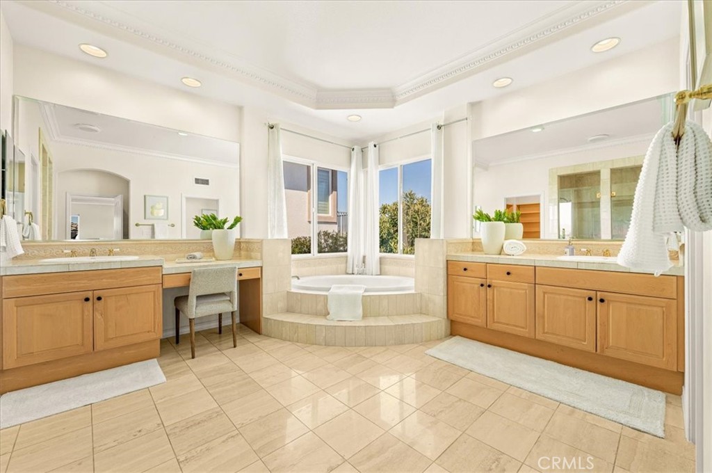 A palatial primary bath with a sunken soaking tub, dual vanities, and a dedicated makeup desk beneath a tray ceiling. - 28932 Drakes Bay, Laguna Niguel CA 92677 - photo 53