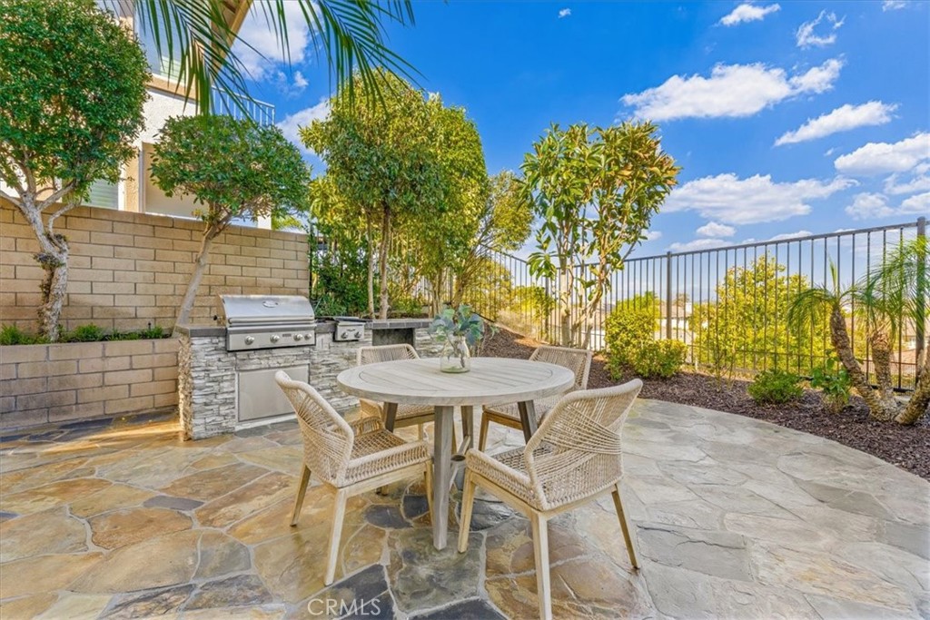 A private flagstone patio framed by lush greenery, with a built-in BBQ and inviting seating for effortless alfresco livi - 28932 Drakes Bay, Laguna Niguel CA 92677 - photo 66