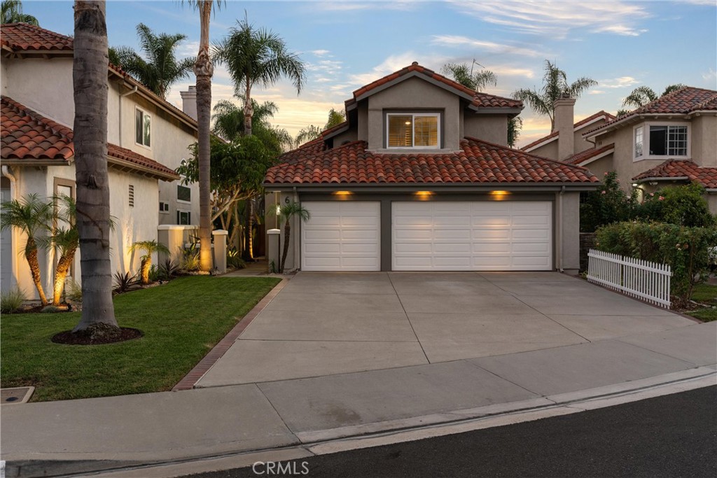 Twilight view showcasing the home’s inviting curb appeal, spacious driveway, three-car garage, and mature palm landscapi - 6 Aleria, Laguna Niguel CA 92677 - photo 1