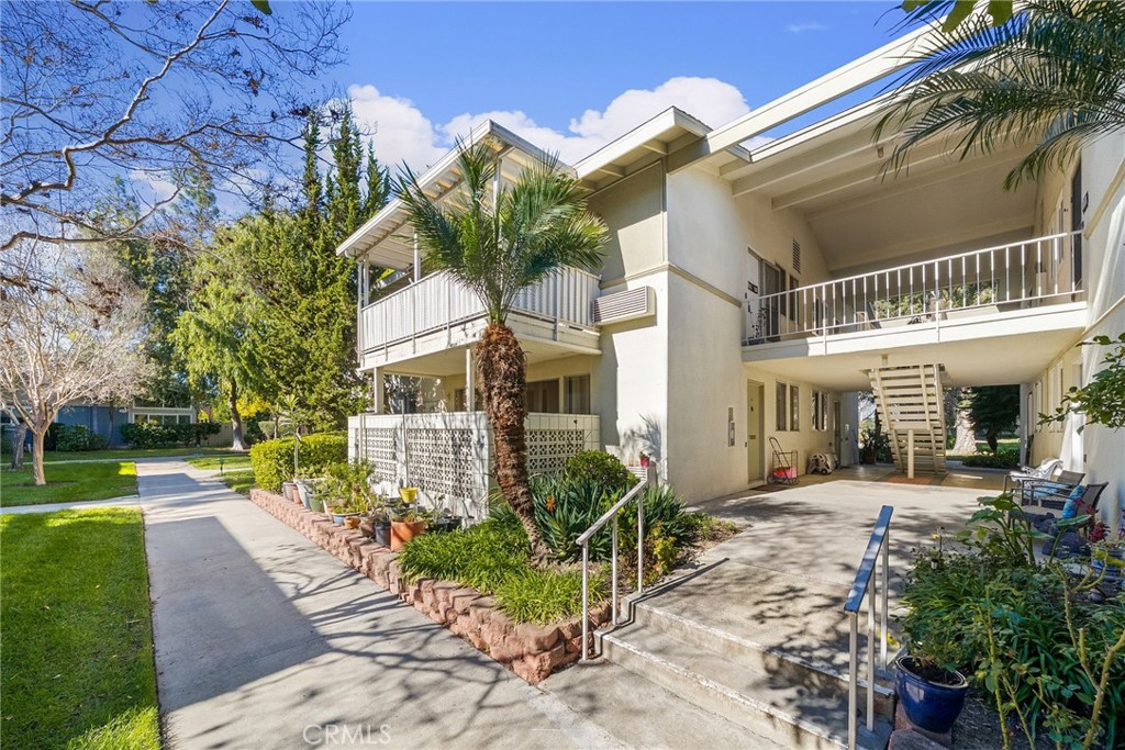 Exterior approach to Building 225, with stairs leading to the upper level and mature landscaping framing the shared entr - 225 Avenida Majorca N, Laguna Woods CA 92637 - photo 28