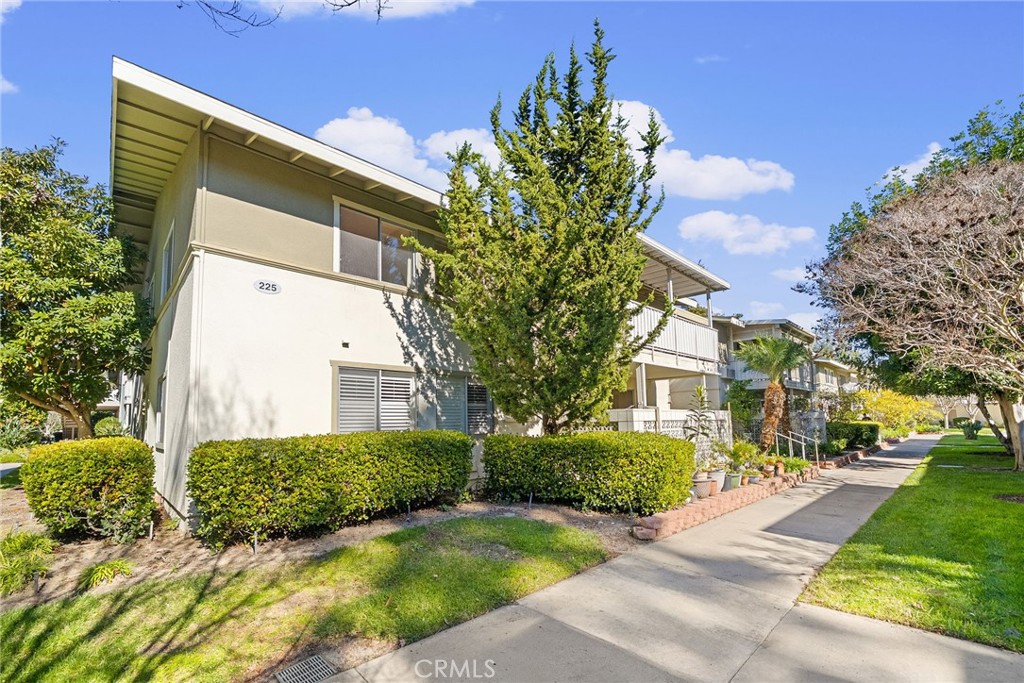 Exterior view of Building 225-N, featuring manicured hedges and mature trees. - 225 Avenida Majorca N, Laguna Woods CA 92637 - photo 30