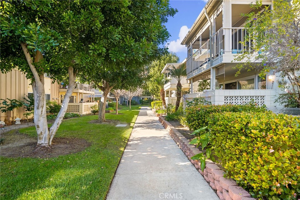 A peaceful, tree-lined walkway leads through the landscaped courtyard toward 225 Avenida Majorca. - 225 Avenida Majorca N, Laguna Woods CA 92637 - photo 31