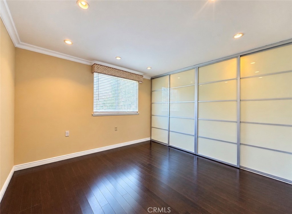The bright second bedroom offers bamboo flooring and a wide closet with sleek glass doors, ideal for guests, a home offi - 2346 Via Mariposa W A, Laguna Woods CA 92637 - photo 17