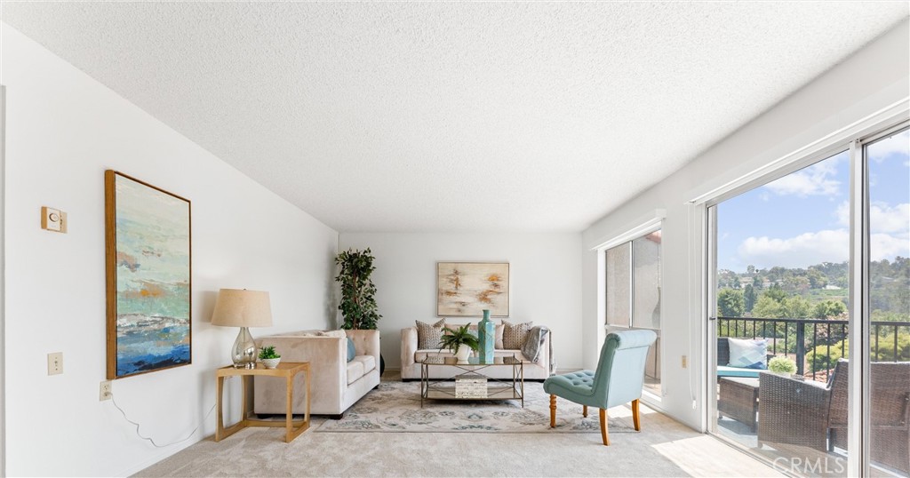 This is a deep living room with panoramic views of the hillsides, sunrise and city views. Staging has been removed. - 3271 San Amadeo P, Laguna Woods CA 92637 - photo 1
