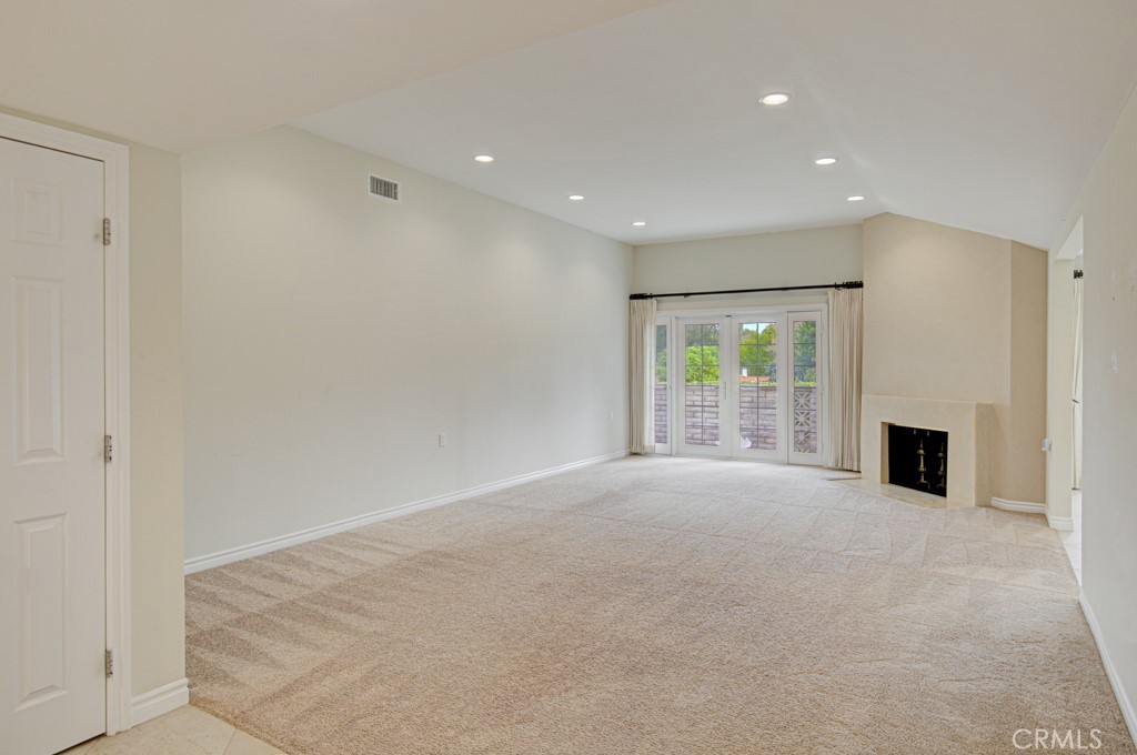 Spacious living room easily accommodates large furnishings. Note the wood-burning fireplace and the double door entry to - 5016 Jardin, Laguna Woods CA 92637 - photo 6