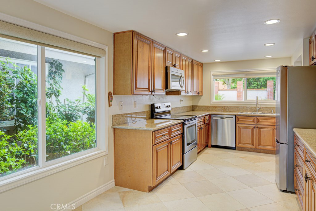 Kitchen has ample storage capacity and features granite countertops and wood cabinetry. - 5016 Jardin, Laguna Woods CA 92637 - photo 13