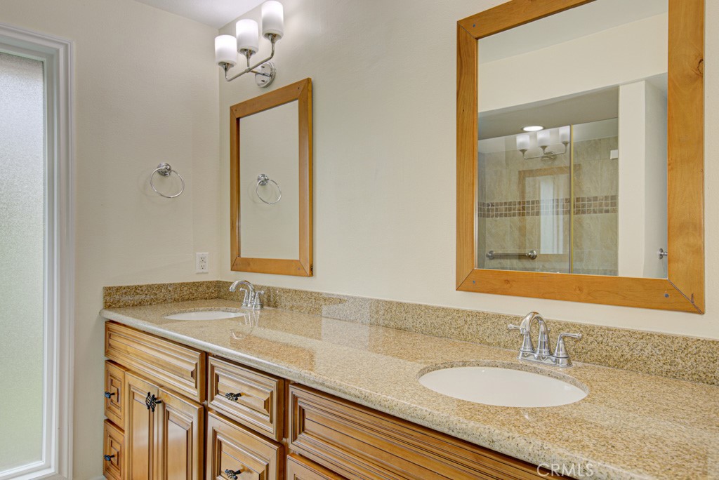 Primary bathroom has dual sinks, granite countertops and wood cabinetry. - 5016 Jardin, Laguna Woods CA 92637 - photo 22
