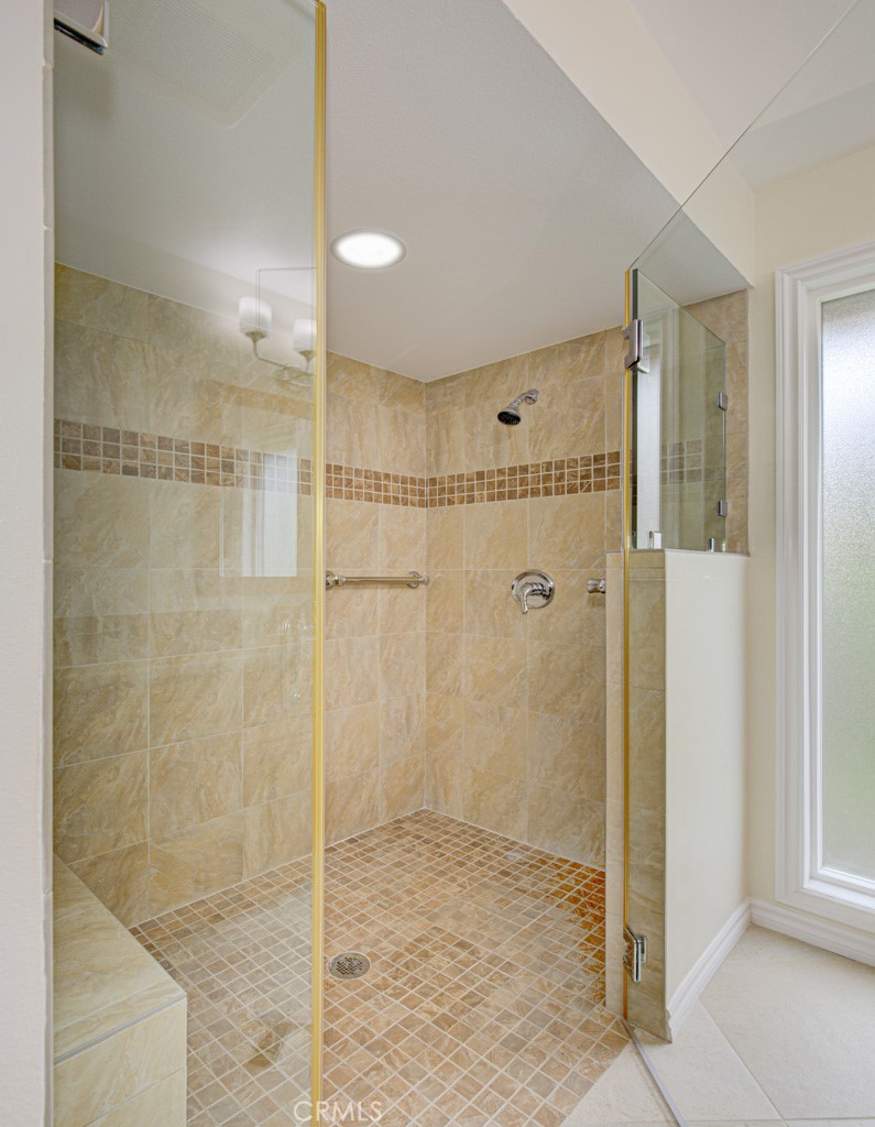 Oversized shower in primary bathroom has a seat and grab bars. - 5016 Jardin, Laguna Woods CA 92637 - photo 23