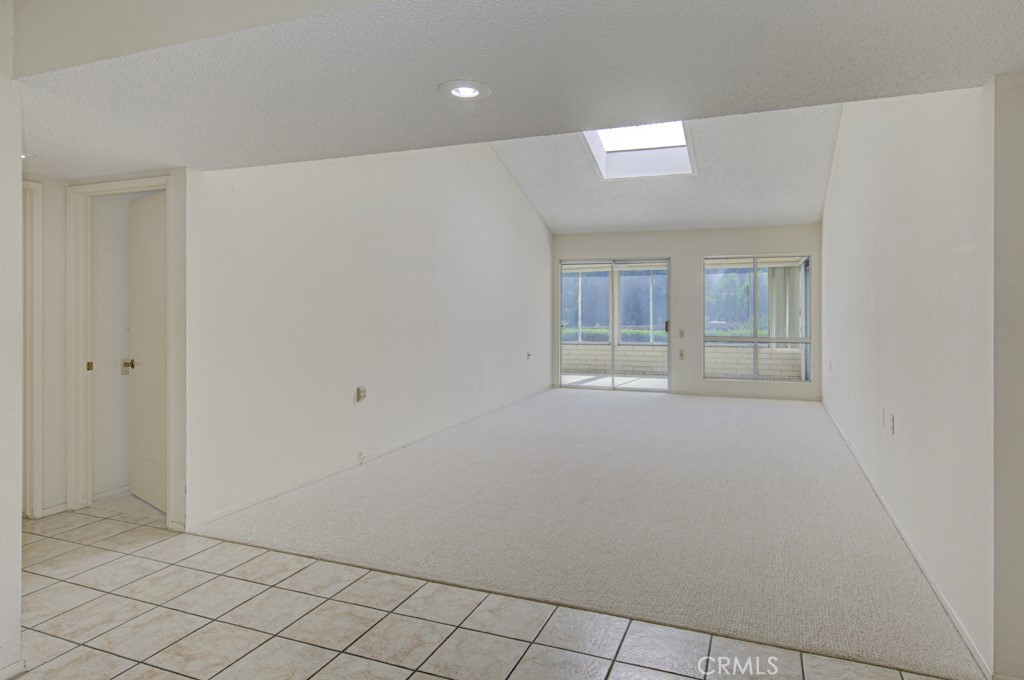 View of the living room from the front entry. The spacious living room has a cathedral ceiling, skylight and direct acce - 5380 Avenida Sosiega B, Laguna Woods CA 92637 - photo 4