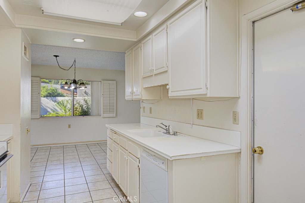 Another view of the kitchen. Access door to the single-car garage can be seen at far right. - 5380 Avenida Sosiega B, Laguna Woods CA 92637 - photo 12