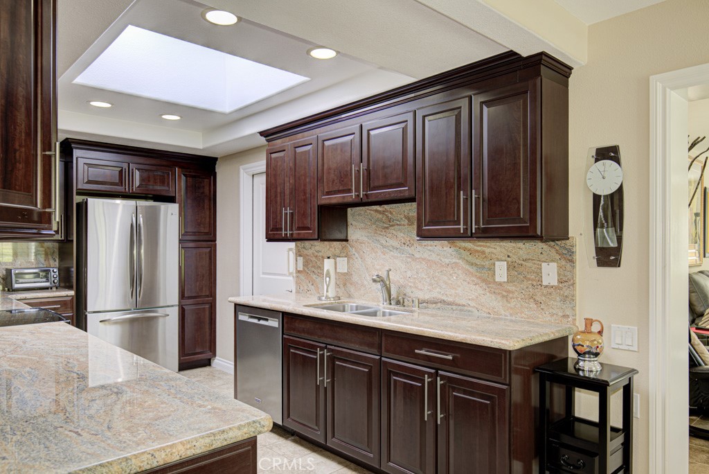 Gorgeous remodeled kitchen has stylish dark wood cabinetry and granite counters/backsplash. Door to the right of the fri - 5516 Paseo Del Lago W A, Laguna Woods CA 92637 - photo 8
