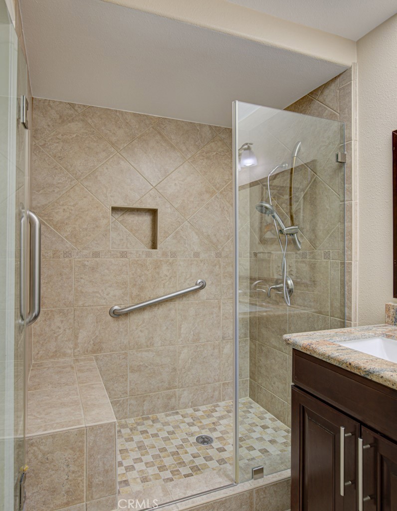 Shower in right-side bathroom has a seat, grab bars and convenient accessory shelf. - 5516 Paseo Del Lago W A, Laguna Woods CA 92637 - photo 19
