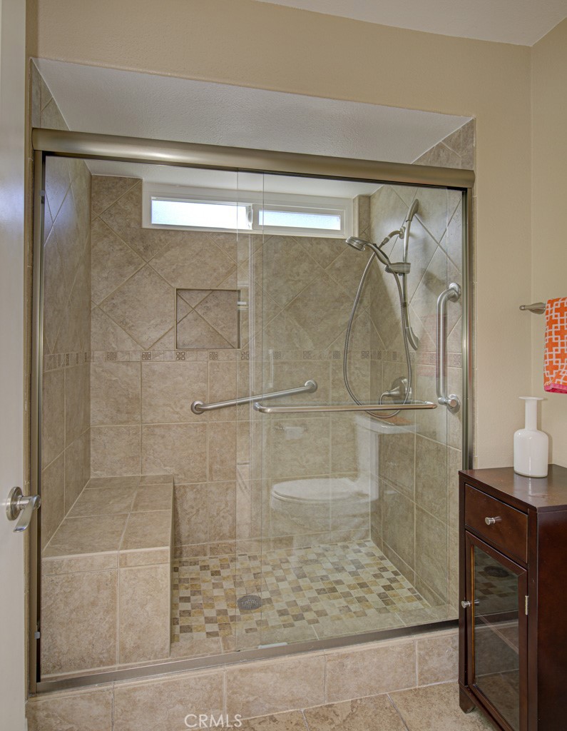 Shower in left-side bathroom has a seat, grab bars and convenient accessory shelf. - 5516 Paseo Del Lago W A, Laguna Woods CA 92637 - photo 26