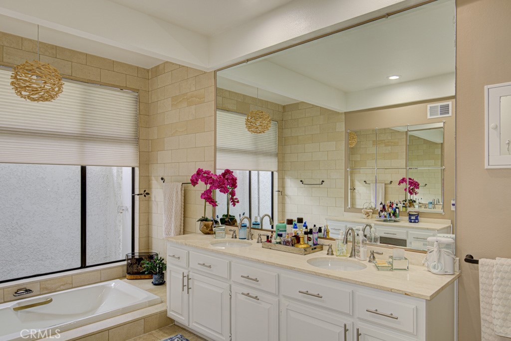 Primary bathroom has dual sinks and a separate tub. - 5553 Rayo Del Sol B, Laguna Woods CA 92637 - photo 28
