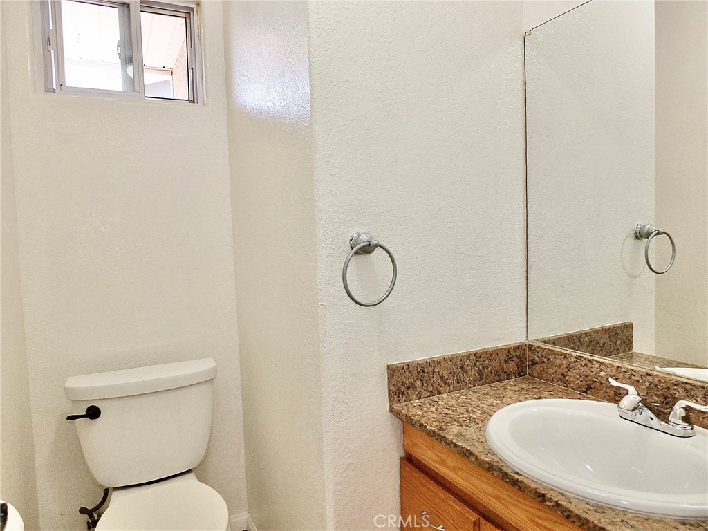 The downstairs half bathroom features a new sink and existing cabinet for storage, mirror and window above toliet - 4441 Farquhar, Los Alamitos CA 90720 - photo 13