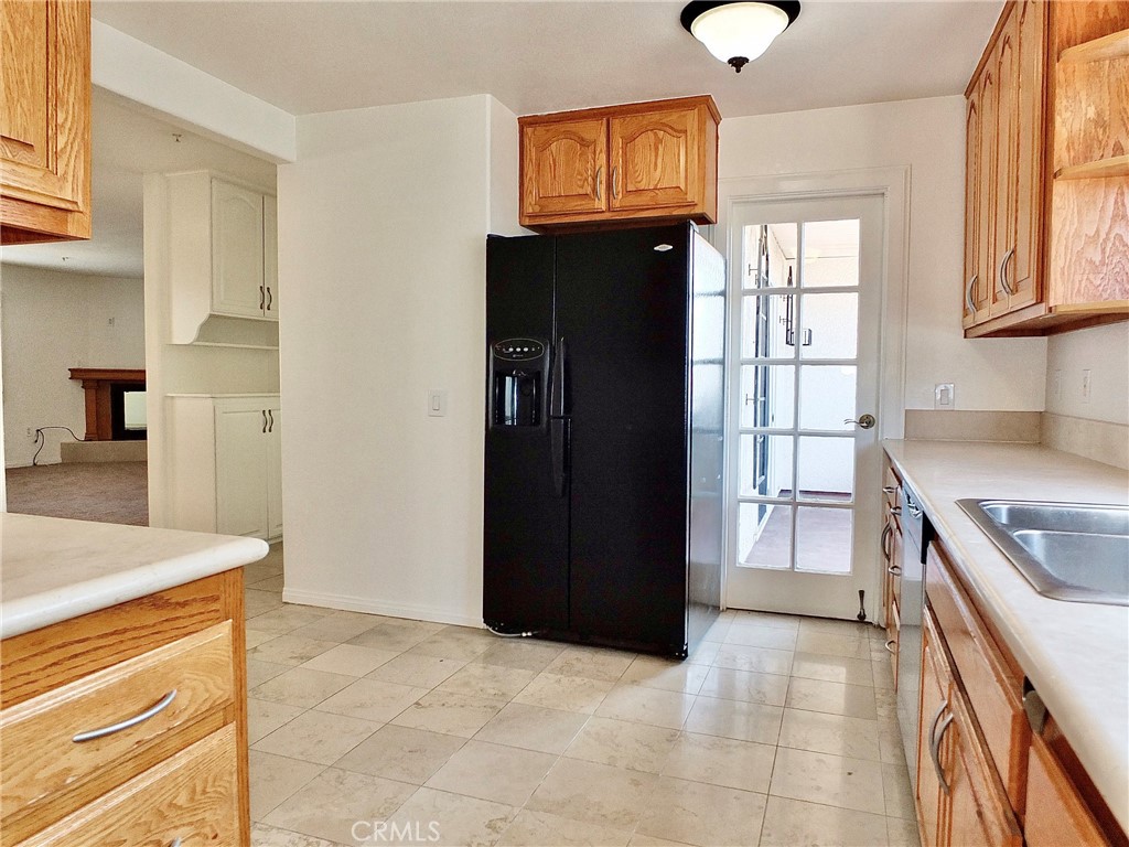 Another view from the kitchen and the stainless steel sink, refrigerator, looks out toward the cabinet off the bathroom, - 4441 Farquhar, Los Alamitos CA 90720 - photo 16