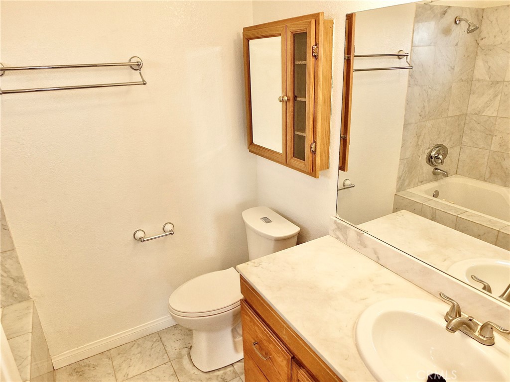 Primary bathroom with vanity and new sink. Storage cabinet above toilet and jet tub/shower. - 4441 Farquhar, Los Alamitos CA 90720 - photo 34