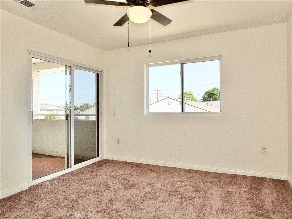 Back bedroom with glass sliding doors leading to balcony and ceiling with fan and lights, plus new carpeting. - 4441 Farquhar, Los Alamitos CA 90720 - photo 40