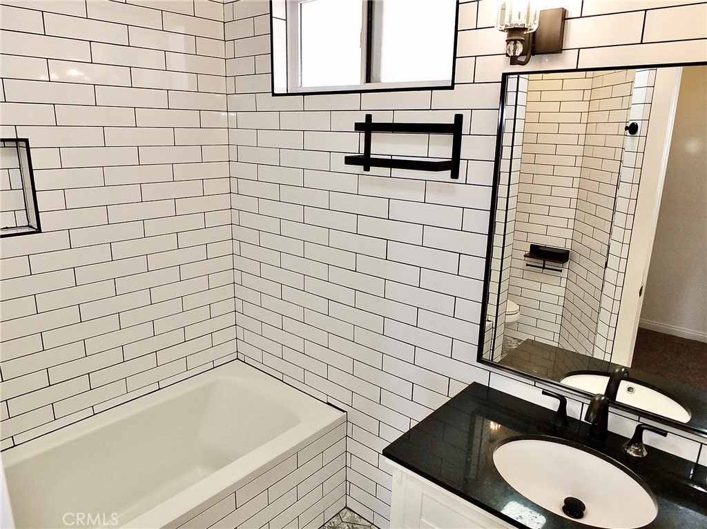 View of tiled upstairs bathroom with tub/shower combo. Lovely vantiy and sink with mirror and lights on both sides , plu - 4441 Farquhar, Los Alamitos CA 90720 - photo 44