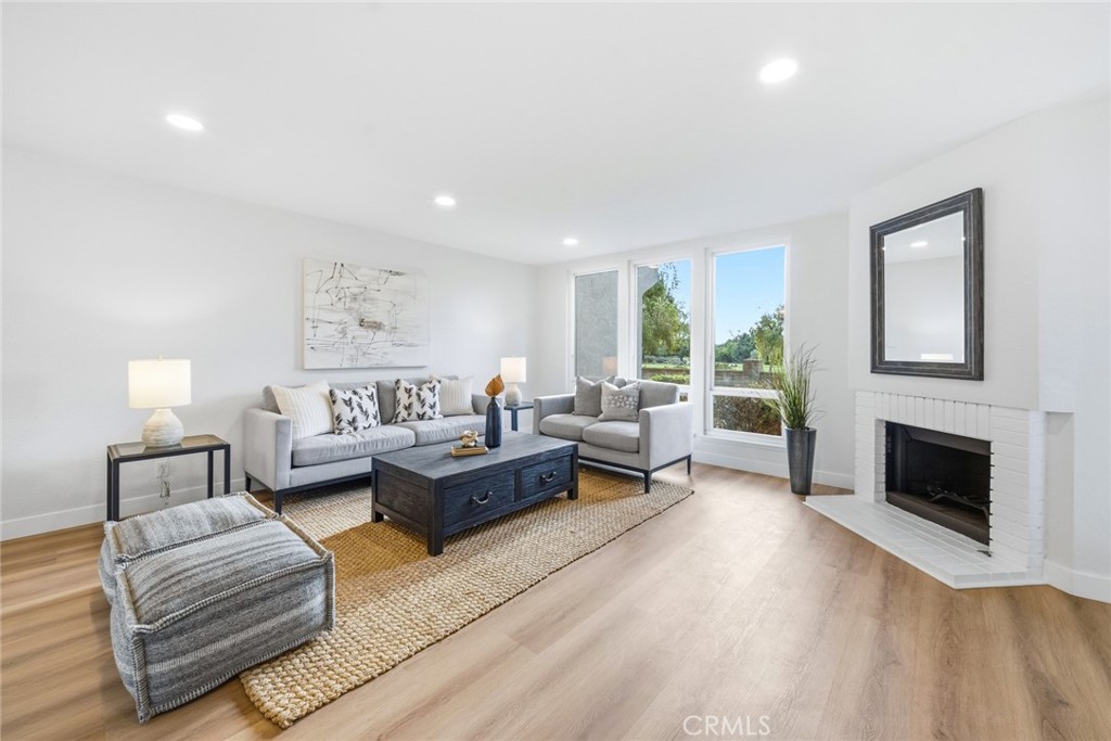 Living room with fireplace, large windows and light-toned flooring. - 25911 Blascos 102, Mission Viejo CA 92691 - photo 6