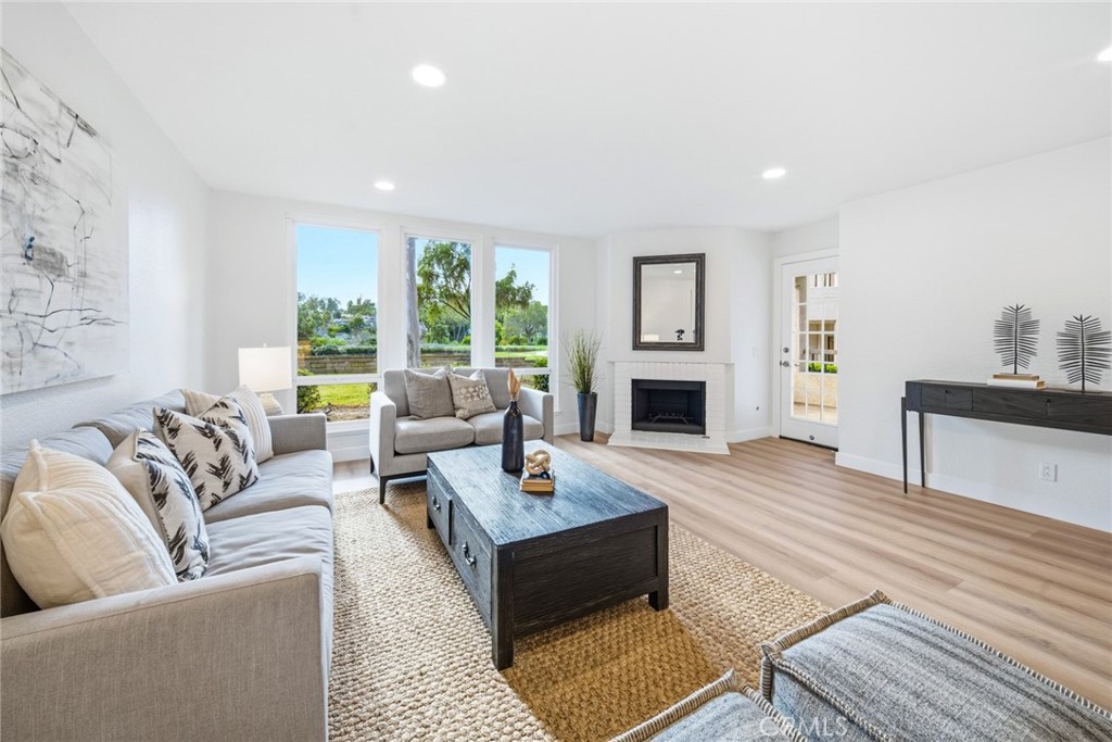 Living room with fireplace and windows overlooking the greenery. - 25911 Blascos 102, Mission Viejo CA 92691 - photo 2