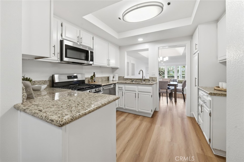 Kitchen with white cabinets, granite counters and stainless microwave. - 25911 Blascos 102, Mission Viejo CA 92691 - photo 14