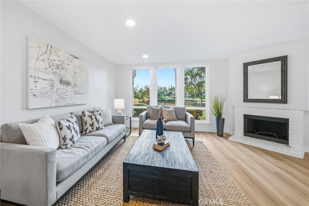Living room with fireplace, sofa seating and windows to the greenery. - 25911 Blascos 102, Mission Viejo CA 92691 - photo 8