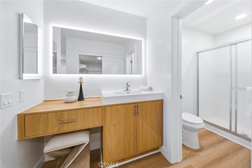 Bathroom with wood vanity, backlit mirror and stall shower. - 25911 Blascos 102, Mission Viejo CA 92691 - photo 28