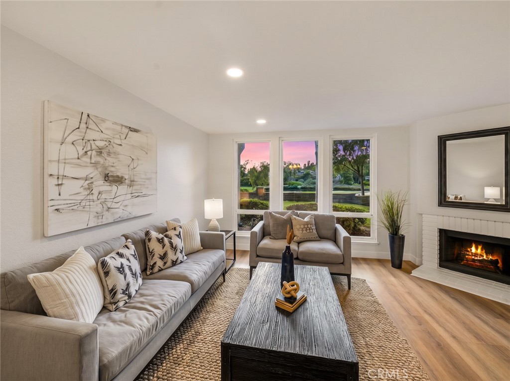 Living room with fireplace and large windows to the greenery. - 25911 Blascos 102, Mission Viejo CA 92691 - photo 30