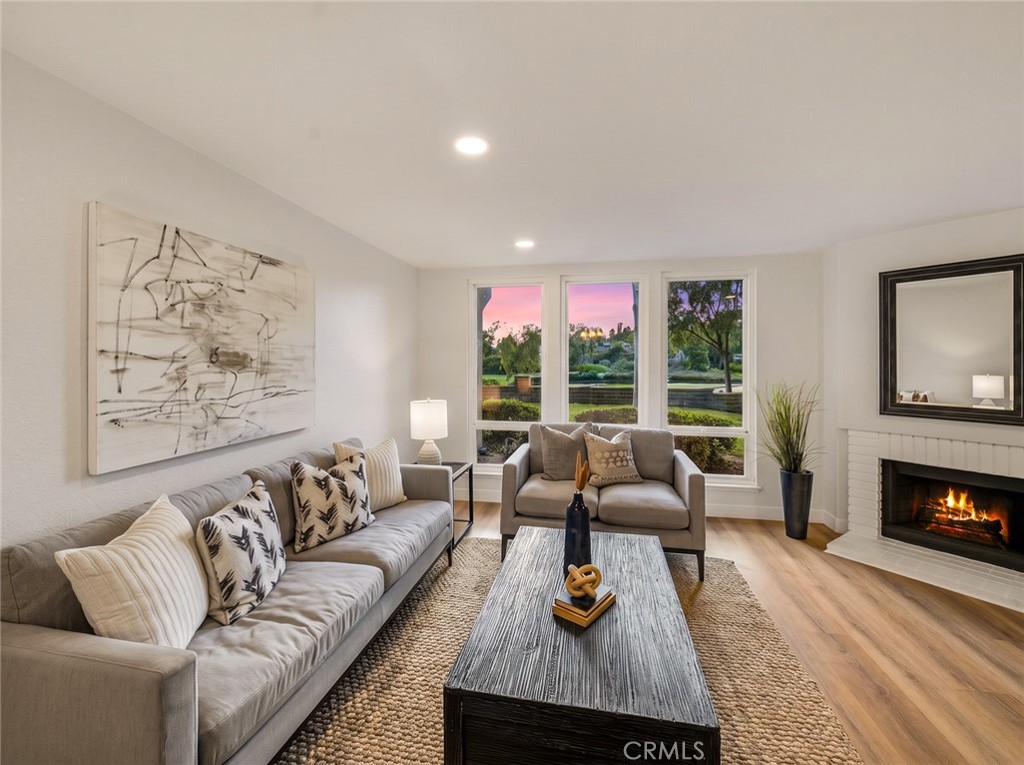 Living room with fireplace and large windows to the greenery. - 25911 Blascos 102, Mission Viejo CA 92691 - photo 31