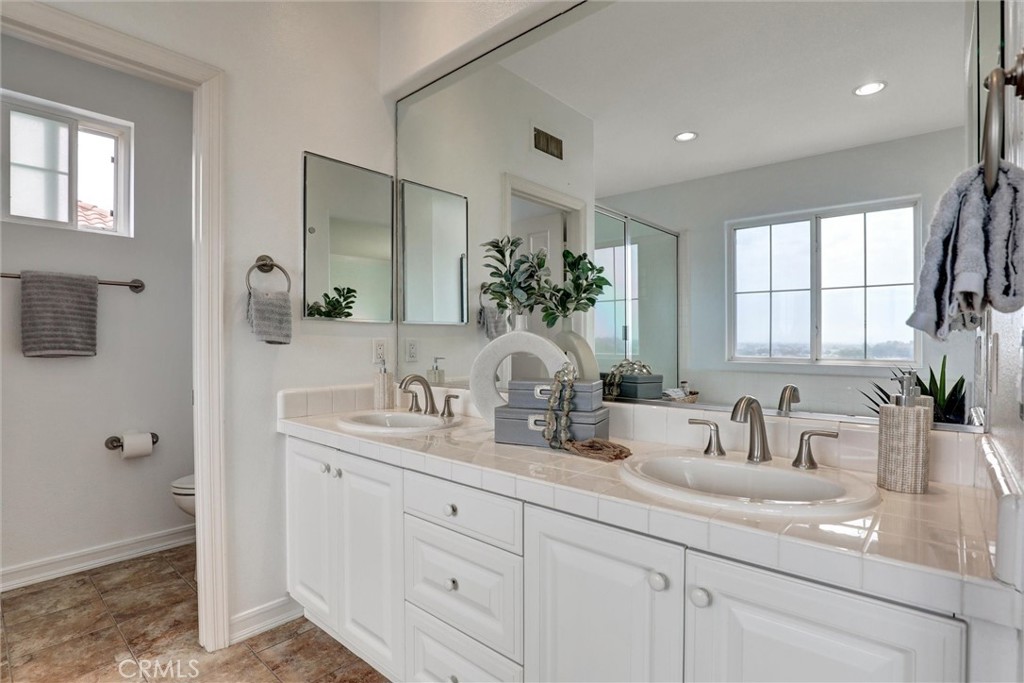 The spacious primary bathroom features dual vanities, a soaking tub, a separate shower, and breathtaking views of the Up - 1402 Sea Ridge Drive, Newport Beach CA 92660 - photo 25