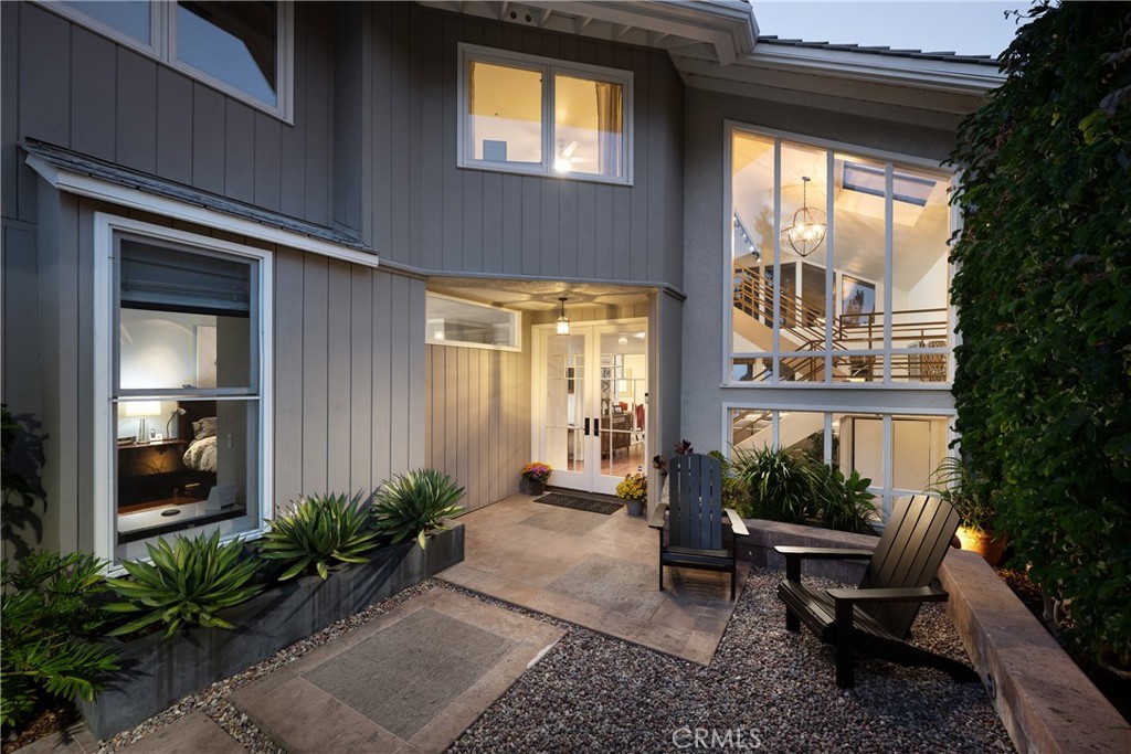 Entry Courtyard: Private entry courtyard framed by established greenery and contemporary hardscape. Expansive windows br - 36 Vienna, Newport Beach CA 92660 - photo 4