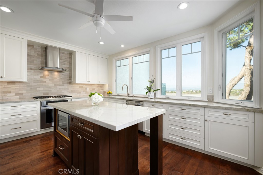 Kitchen: Light-filled kitchen pairs crisp white cabinetry with a contrasting center island, stone countertops, stainless - 36 Vienna, Newport Beach CA 92660 - photo 7