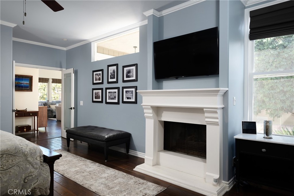Primary Bedroom: Additional view of the primary bedroom highlights a fireplace with classic mantel, rich wood flooring, - 36 Vienna, Newport Beach CA 92660 - photo 17