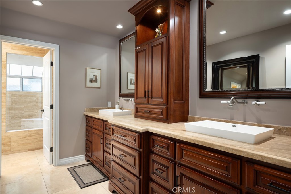 Primary Bathroom: Spacious primary bath features dual vessel sinks, extensive wood cabinetry, stone countertops, oversiz - 36 Vienna, Newport Beach CA 92660 - photo 19