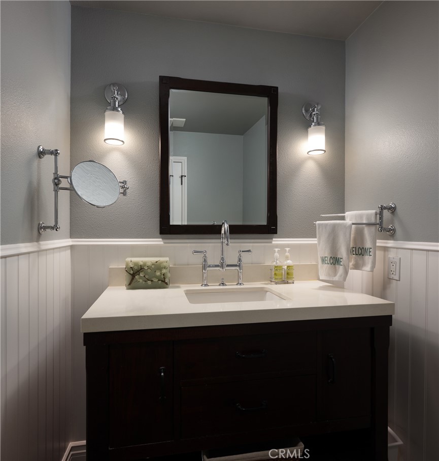 Powder Bathroom Vanity: Updated vanity area features a dark wood cabinet, light countertop with undermount sink, polishe - 36 Vienna, Newport Beach CA 92660 - photo 21