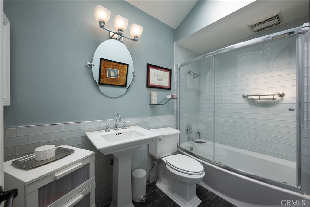 Bathroom: Full bathroom features a pedestal sink, tub-and-shower combination with glass enclosure, and light-toned subwa - 36 Vienna, Newport Beach CA 92660 - photo 28