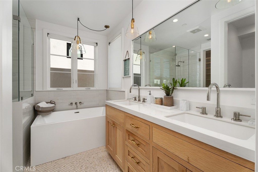 Primary Bathroom: Double vanity with wood vanity cabinetry and quartz countertops. Decorator tile on floor - 418 1/2 Larkspur, Newport Beach CA 92625 - photo 17