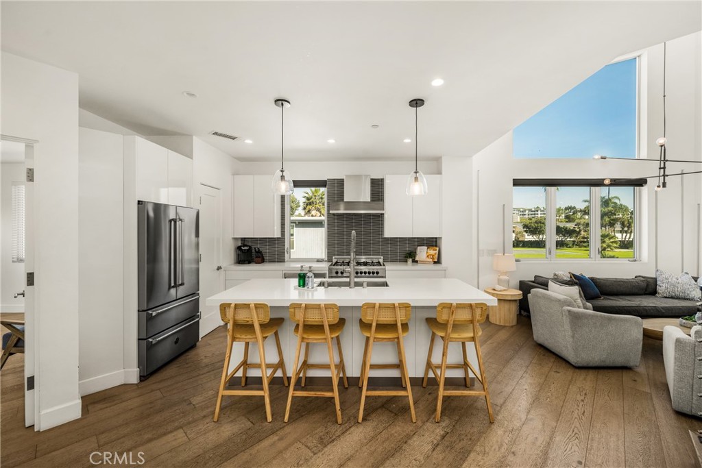 The chef’s kitchen is appointed with quartz countertops, a generous center island, modern European-style cabinetry, and - 4405 Channel Place, Newport Beach CA 92663 - photo 15