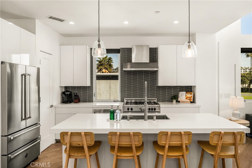 The chef’s kitchen is appointed with quartz countertops, a generous center island, modern European-style cabinetry, and - 4405 Channel Place, Newport Beach CA 92663 - photo 16