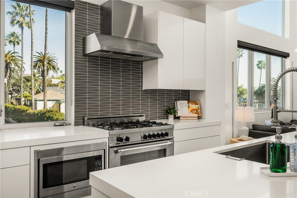 The chef’s kitchen is appointed with quartz countertops, a generous center island, modern European-style cabinetry, and - 4405 Channel Place, Newport Beach CA 92663 - photo 18